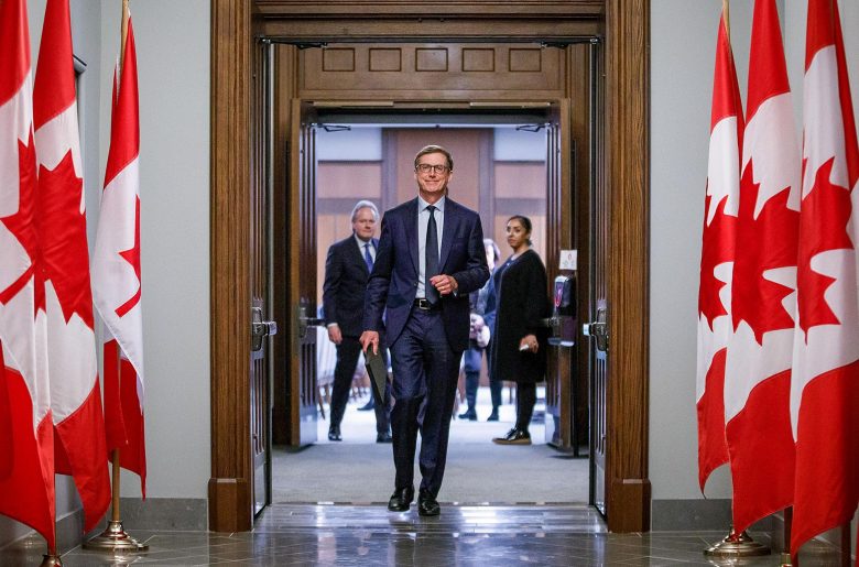 Tiff Macklem walking confidently into the House of Commons. Canadian flags line the hallway.