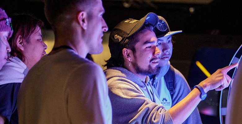 Five Indigenous teenagers looking at a screen together.