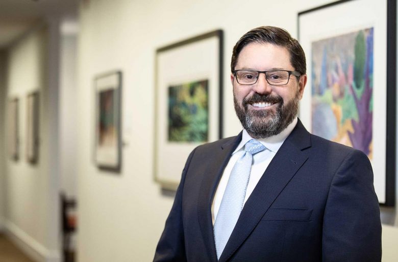 Filipe Dinis smiling, standing in a hallway with framed artwork on the walls behind him.