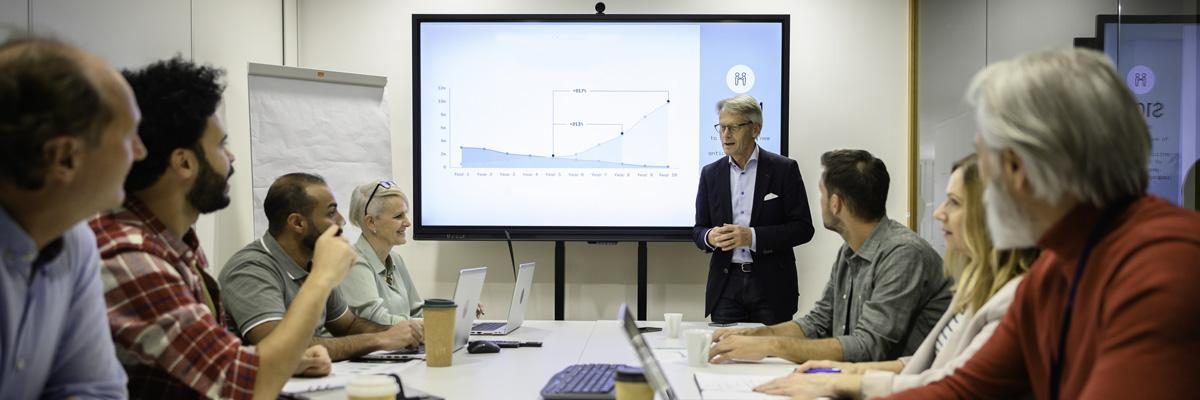 A group of professional employees is attending a meeting in a boardroom. 